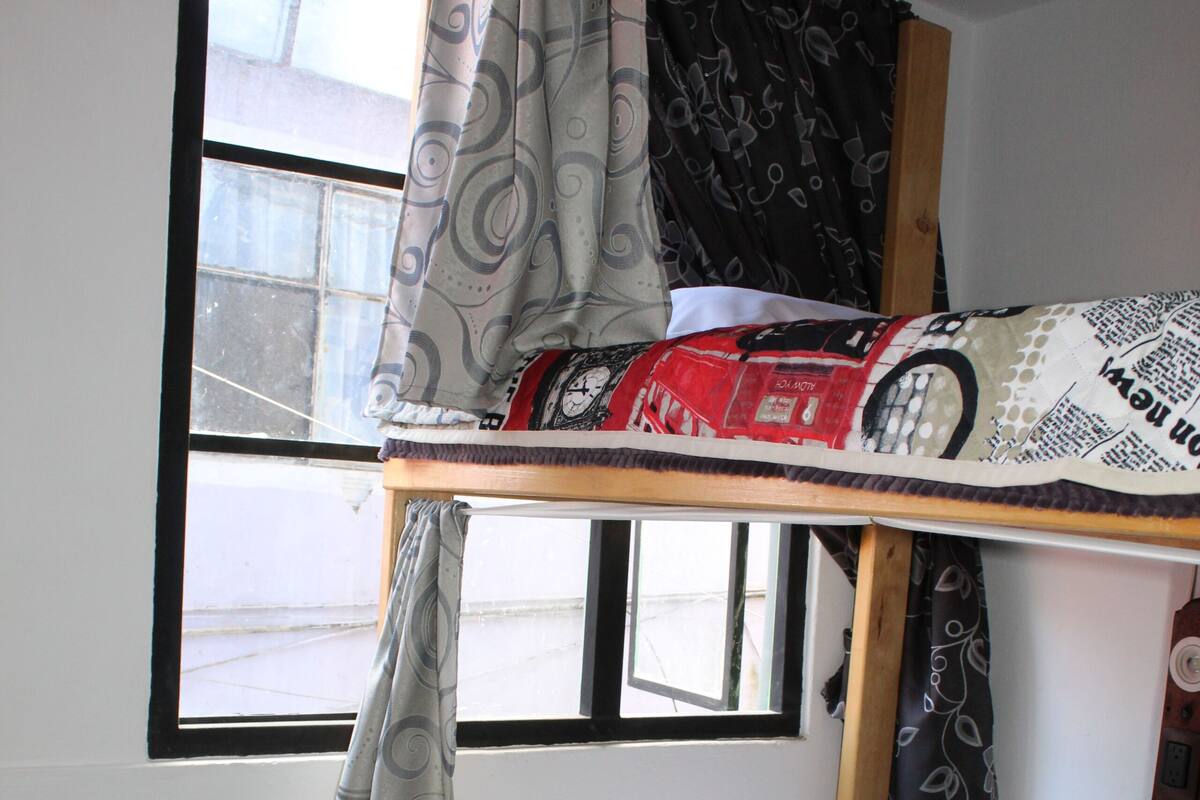 Ein Etagenbett mit einem gemusterten Bettbezug und einem Fenster mit Vorhängen.