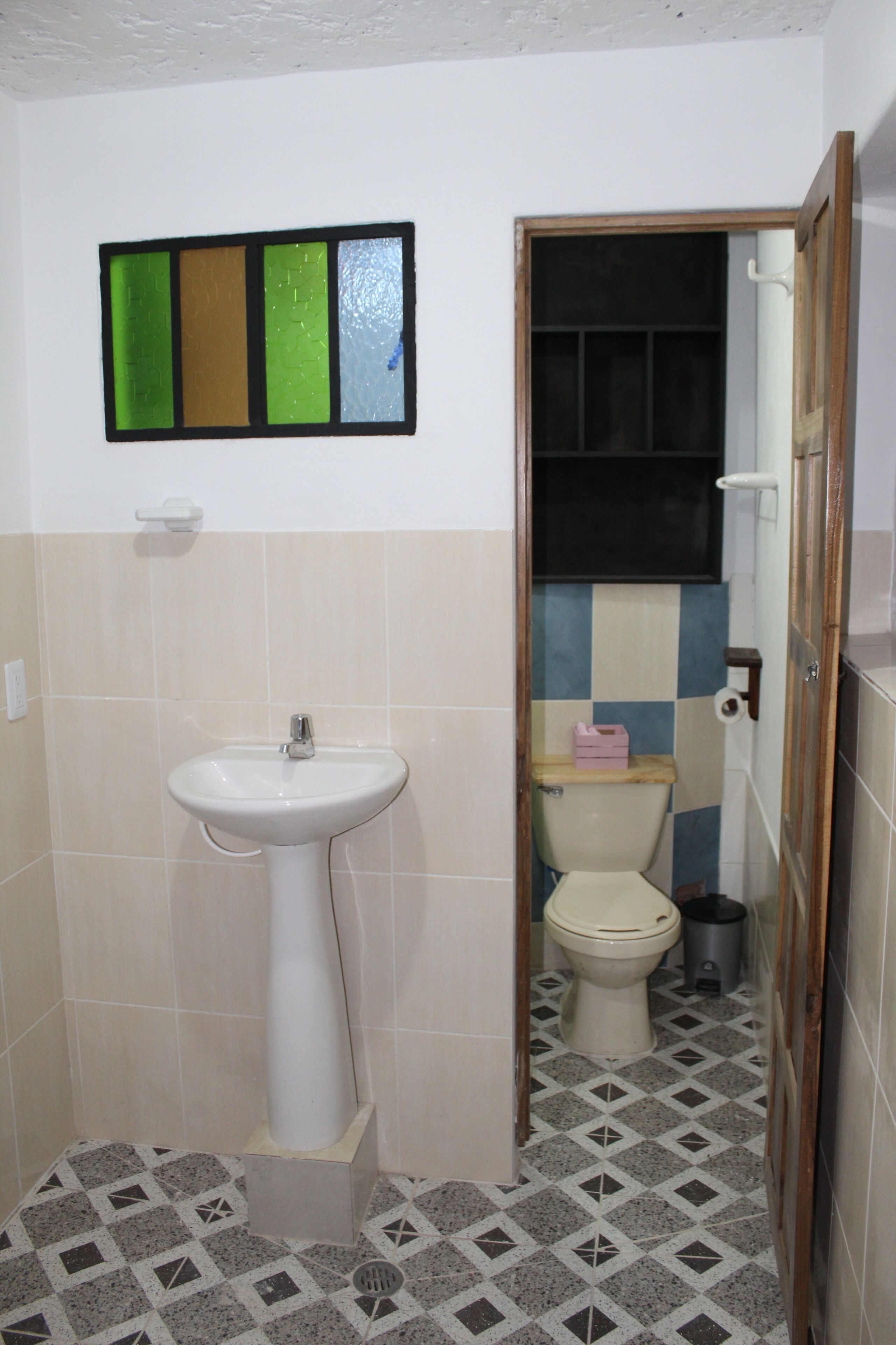 A small bathroom with a sink, toilet, and a tiled floor.