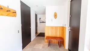 Um corredor com um banco de madeira, um porta-roupas e uma luminária na parede.