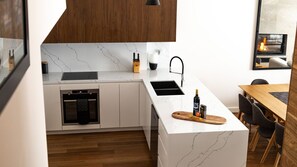 A modern kitchen with a built-in oven, a sink, and a dining area with a wooden table and chairs.