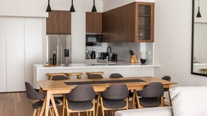 Une cuisine moderne avec des meubles en bois, un îlot central et un coin repas comprenant une table et des chaises.