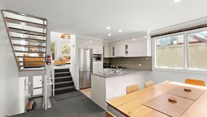 Una cocina moderna con una isla central, electrodomésticos integrados y un comedor con mesa y sillas de madera.