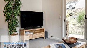 Relax in this stylish living room with a flat-screen TV, a potted plant, and a comfortable coffee table.