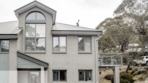 Ein modernes, zweistöckiges Haus mit Balkon, großen Fenstern und einer Garage.