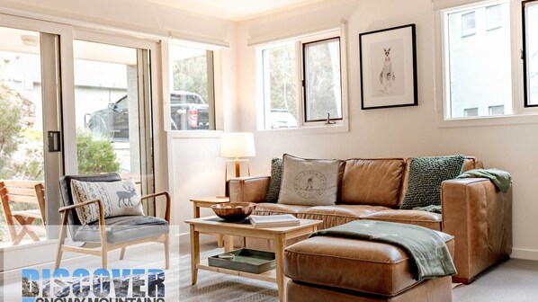 Relax in this stylish living room with a leather sofa, wooden coffee table, and a comfortable ottoman.