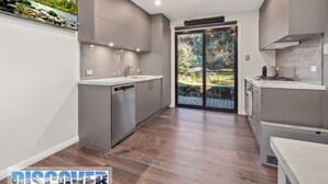 A modern kitchen with grey cabinetry, a dishwasher, and a built-in oven. - Snow Creek 4 - Thredbo (Thredbo)