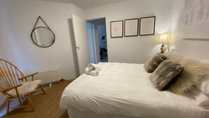 A bedroom with a bed, a chair, a radiator, and a door leading to another room. - Sitzmark 1 - Central Village location (Thredbo)