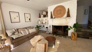 A living room with a fireplace, a sofa, a coffee table, and decorative items. - Sitzmark 1 - Central Village location (Thredbo)