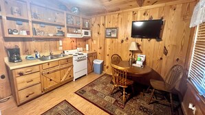 A wooden-paneled kitchen with a stove, microwave, and coffee maker. There is a dining table with chairs and a rug. - The Old Home Place in amazing Mountain View, close to the courthouse square (Mountain View)