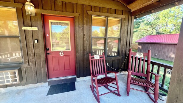 A wooden cabin with a red door, two rocking chairs, and a porch with a metal railing. - The Old Home Place in amazing Mountain View, close to the courthouse square (Mountain View)