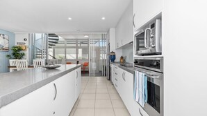 A modern kitchen with white cabinetry, stainless steel appliances, and a central island.
