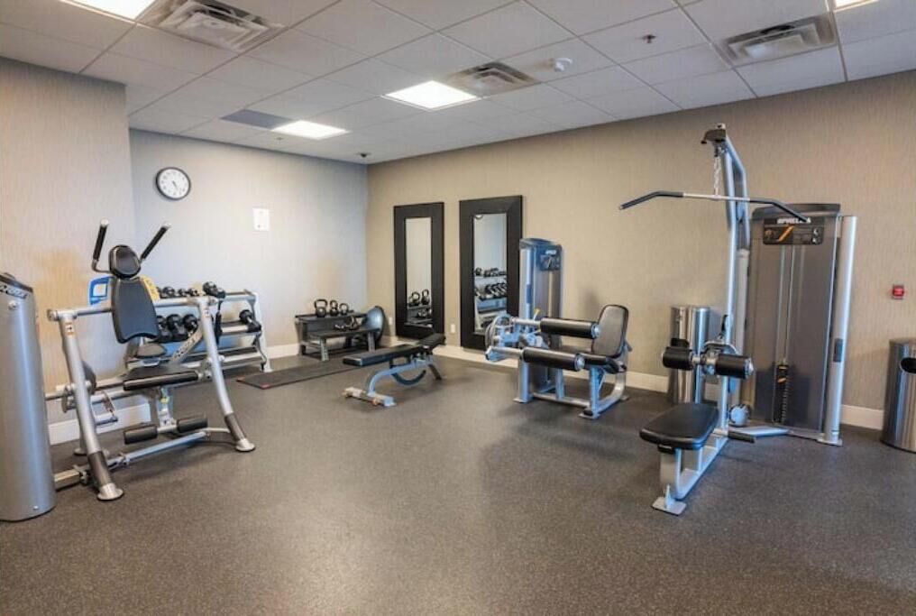 Et fitnesscenter med forskellig træningsudstyr, herunder løbebånd, styrkemaskiner og håndvægte.