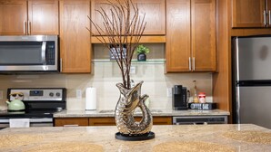 A kitchen with wooden cabinets, a microwave, a coffee bar, and a decorative vase on the counter. - Cozy Retreat with Rooftop Pool, Parking, and Spacious Comfort (Dallas)