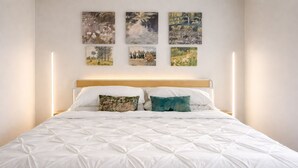 Ein Bett mit weißer gesteppter Decke, zwei Kissen und einem Holz-Kopfteil.