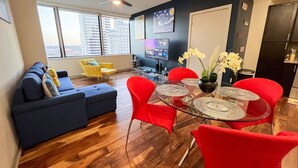 Ein modernes Wohnzimmer mit einem Glastisch, roten Stühlen, einem blauen Sofa und einem gelben Sessel.