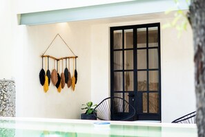 A room with a black door, a hanging wall decoration, and a small potted plant. - Charming 2-bedroom house with AC, WiFi in tranquil Mérida (Mérida)