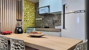 A modern kitchen with a built-in microwave, a refrigerator, and a blender on the counter. - Perto da Praia: Wi-Fi, Piscina e Garagem (Maceió)