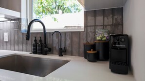 A modern kitchen with a stainless steel sink, black faucets, and a coffee machine. - Htown eclectic funk vibe A (Houston)