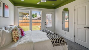 A bedroom with a bed, a ceiling fan, and a view of the backyard through a sliding glass door. - Htown eclectic funk vibe A (Houston)