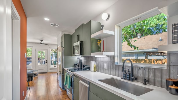 A modern kitchen with a large island, built-in appliances, and a window with a view of the outside. - Htown eclectic funk vibe A (Houston)