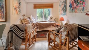 A cozy bedroom with a bed, two rocking chairs, a desk, and a window with blinds. - Nice home in Härryda with WiFi (Härryda)
