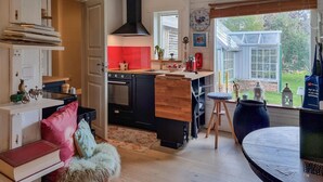 A cozy kitchen with a wooden island, a red accent wall, and a view of the garden. - Nice home in Härryda with WiFi (Härryda)