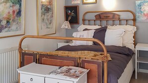 A bedroom with a wooden bed frame, a bedside table with a lamp, and a small desk with a newspaper. - Nice home in Härryda with WiFi (Härryda)