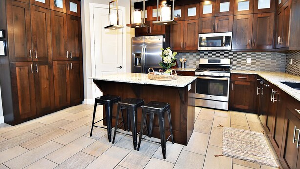 Una cocina moderna con armarios de madera oscura, electrodomésticos de acero inoxidable y una isla central con taburetes.