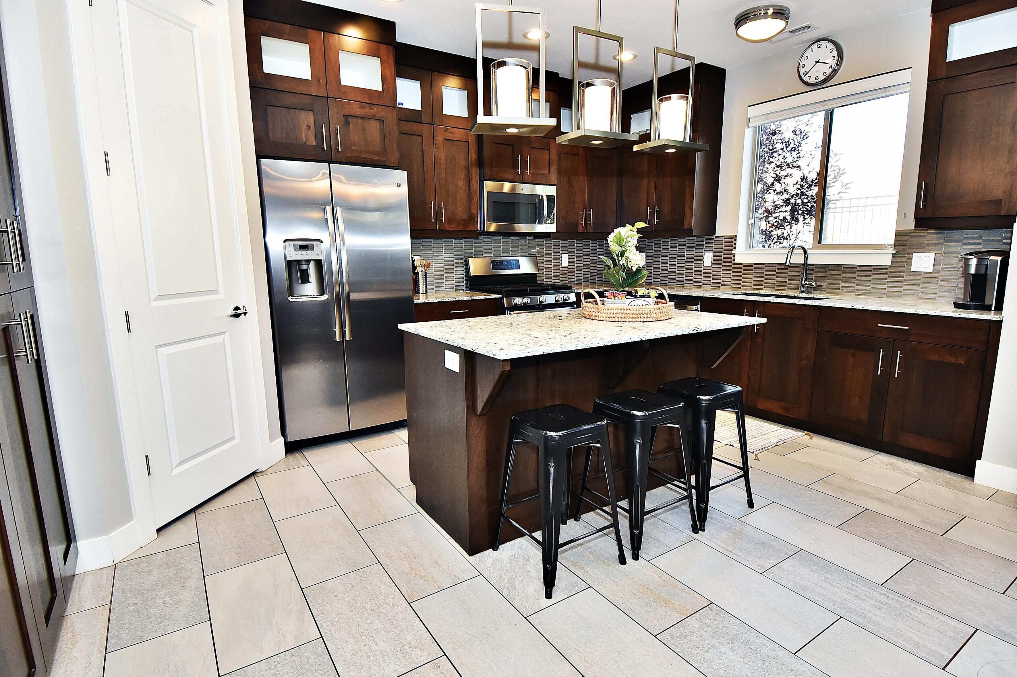 A modern kitchen with dark wood cabinets, stainless steel appliances, and a central island with bar stools.