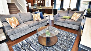 Una sala de estar moderna con dos sofás grises, una mesa de centro y una alfombra estampada.