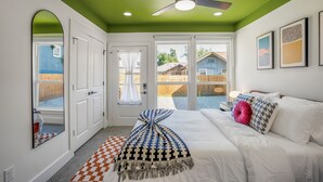 A bedroom with a bed, a ceiling fan, and a view of the backyard through a sliding glass door.