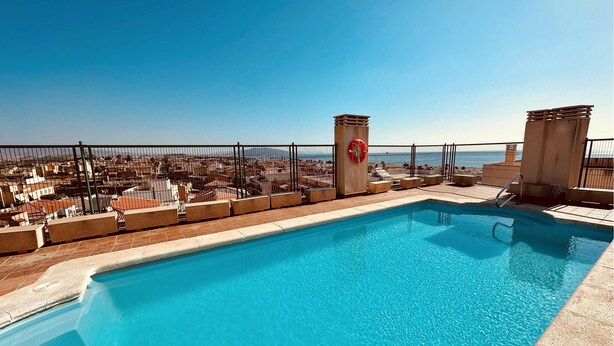 A rooftop pool with a clear view of the cityscape and the ocean.