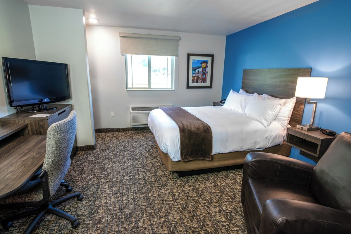 Une chambre d’hôtel équipée d’un lit, d’un bureau, d’une chaise, d’une télévision et d’une fenêtre donnant sur un paysage agréable.