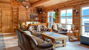 A cozy log cabin interior with leather furniture, a fireplace, and a view of the outdoors. - Stunning home in Todalen (Todalen)