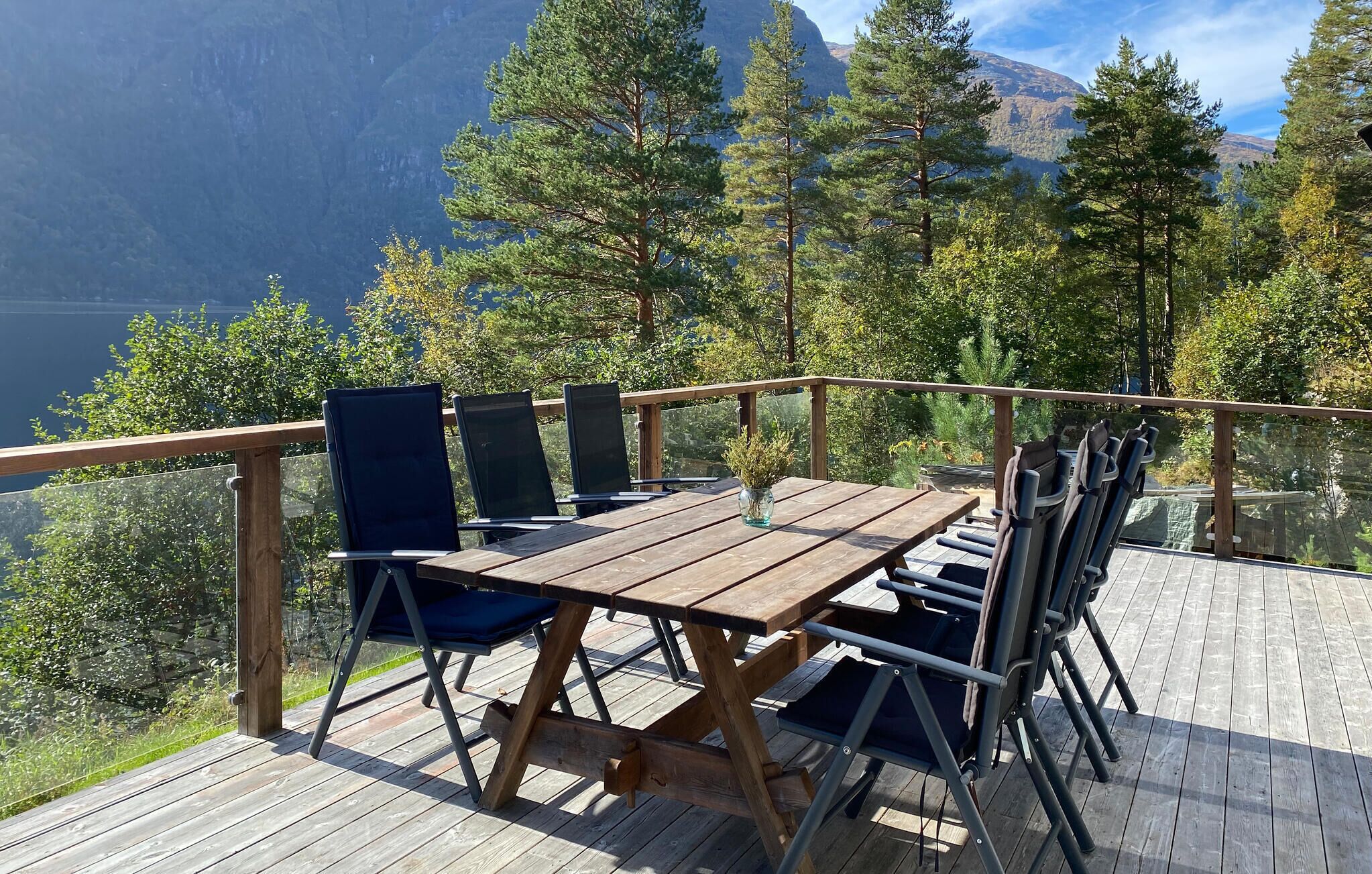 Une terrasse en bois avec une table et des chaises, offrant une vue sur un paysage montagneux.