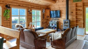 A cozy log cabin interior with a wooden bench, leather sofas, a television, and a bookshelf. - Stunning home in Todalen (Todalen)