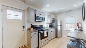 Una cocina moderna con electrodomésticos de acero inoxidable, encimeras de granito y armarios blancos.
