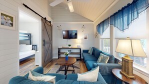 Una sala de estar acogedora con un sofá azul, una mesa de centro de madera y un televisor en la pared.