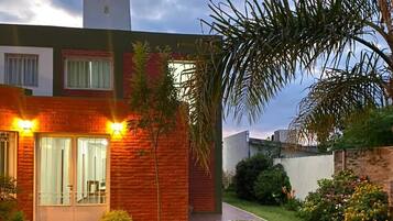 A modern house with a brick exterior, a small lawn, and outdoor furniture.