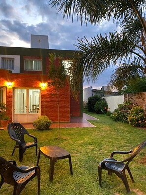 A modern house with a brick exterior, a small lawn, and outdoor furniture.