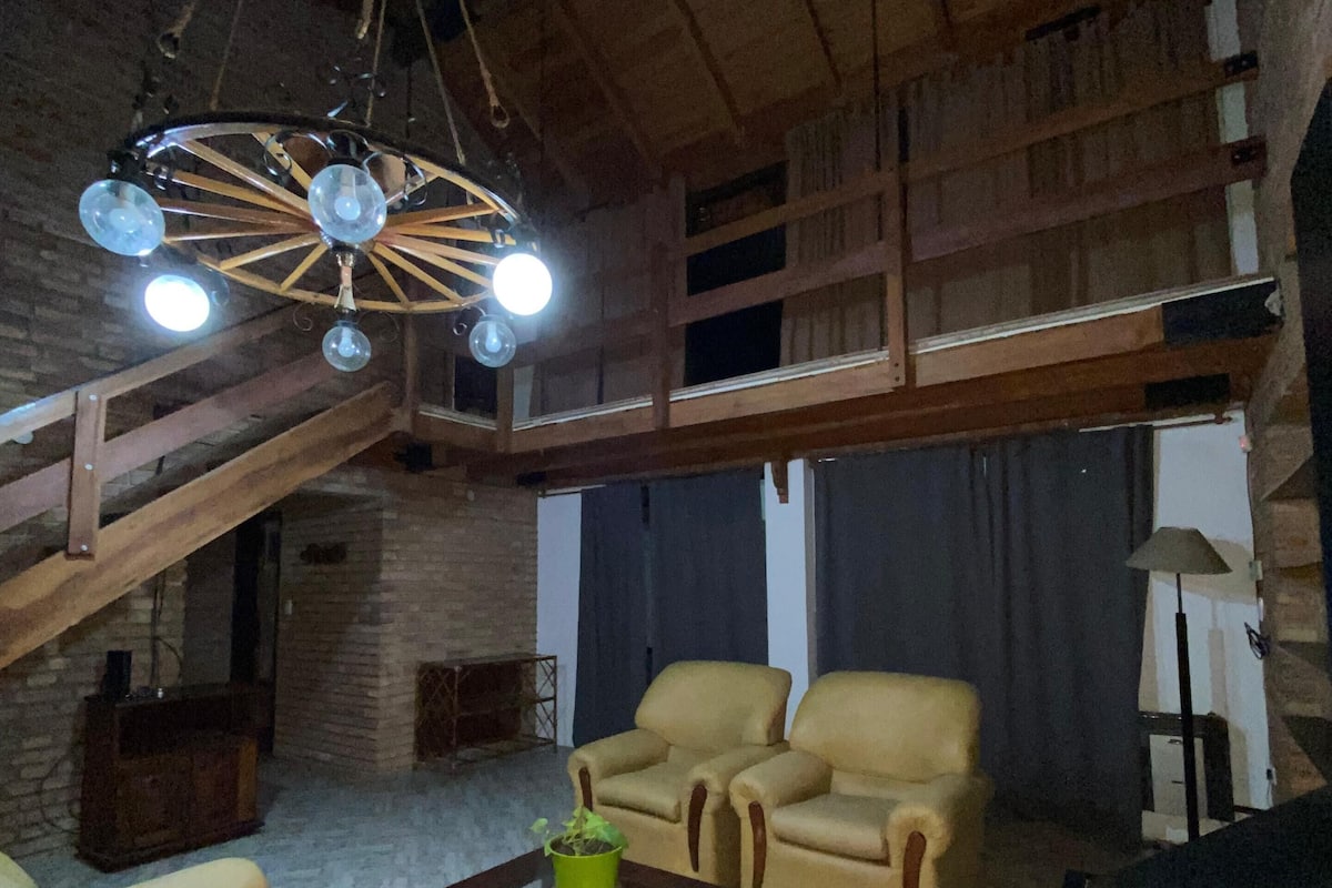 A spacious living area with high ceilings, a fireplace, and a staircase.