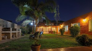 A well-lit outdoor patio area with a lawn, seating, and a potted plant. - Posada d'lua (Villa Carlos Paz)