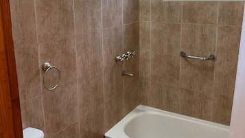 Bañera con ducha, toallas, papel higiénico