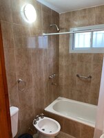 Bañera con ducha, toallas, papel higiénico