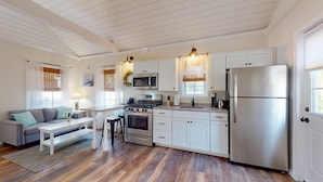 A modern kitchen with white cabinets, stainless steel appliances, and a wooden floor. - Coastal Estate – Private Cottage with King Bed & Pool Access (Cape May)