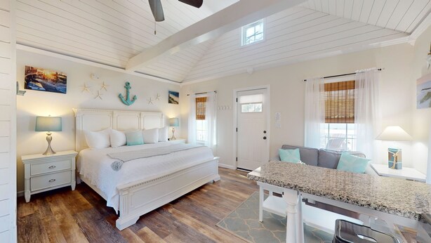 A spacious bedroom with a large bed, a wooden floor, a dining area, and nautical decor. - Coastal Estate – Private Cottage with King Bed & Pool Access (Cape May)