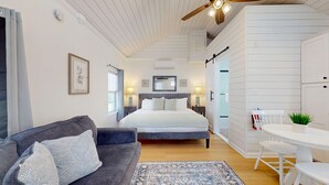 Un dormitorio moderno con una cama grande, un sofá, una mesa de comedor y un ventilador de techo.