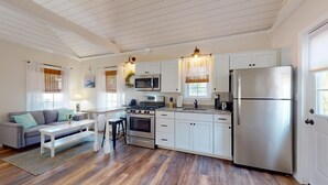 A modern kitchen with white cabinets, stainless steel appliances, and a wooden floor.