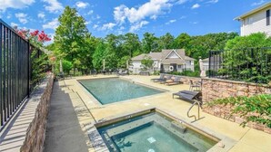 A swimming pool area with lounge chairs and a stone wall. - Luxury Lake Martin Condo  (Dadeville)
