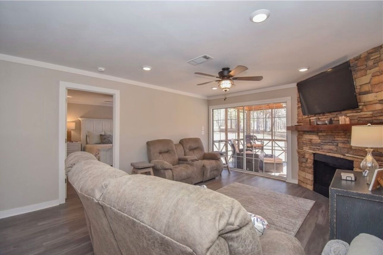 A living room with a large sectional sofa, a fireplace, a flat-screen TV, and a ceiling fan.